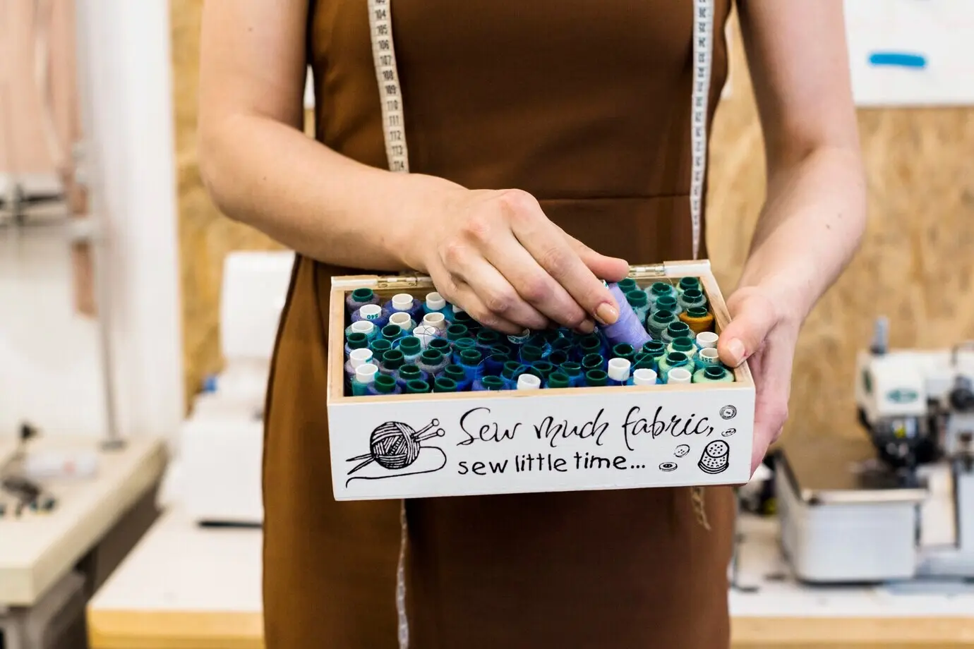 Средний план: рука модельера выбирает нитку из контейнера.